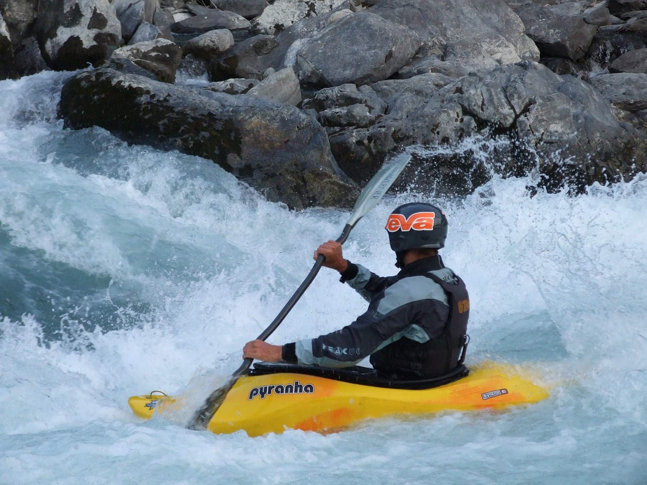 man kayaking on river rapids with kayak insurance cover