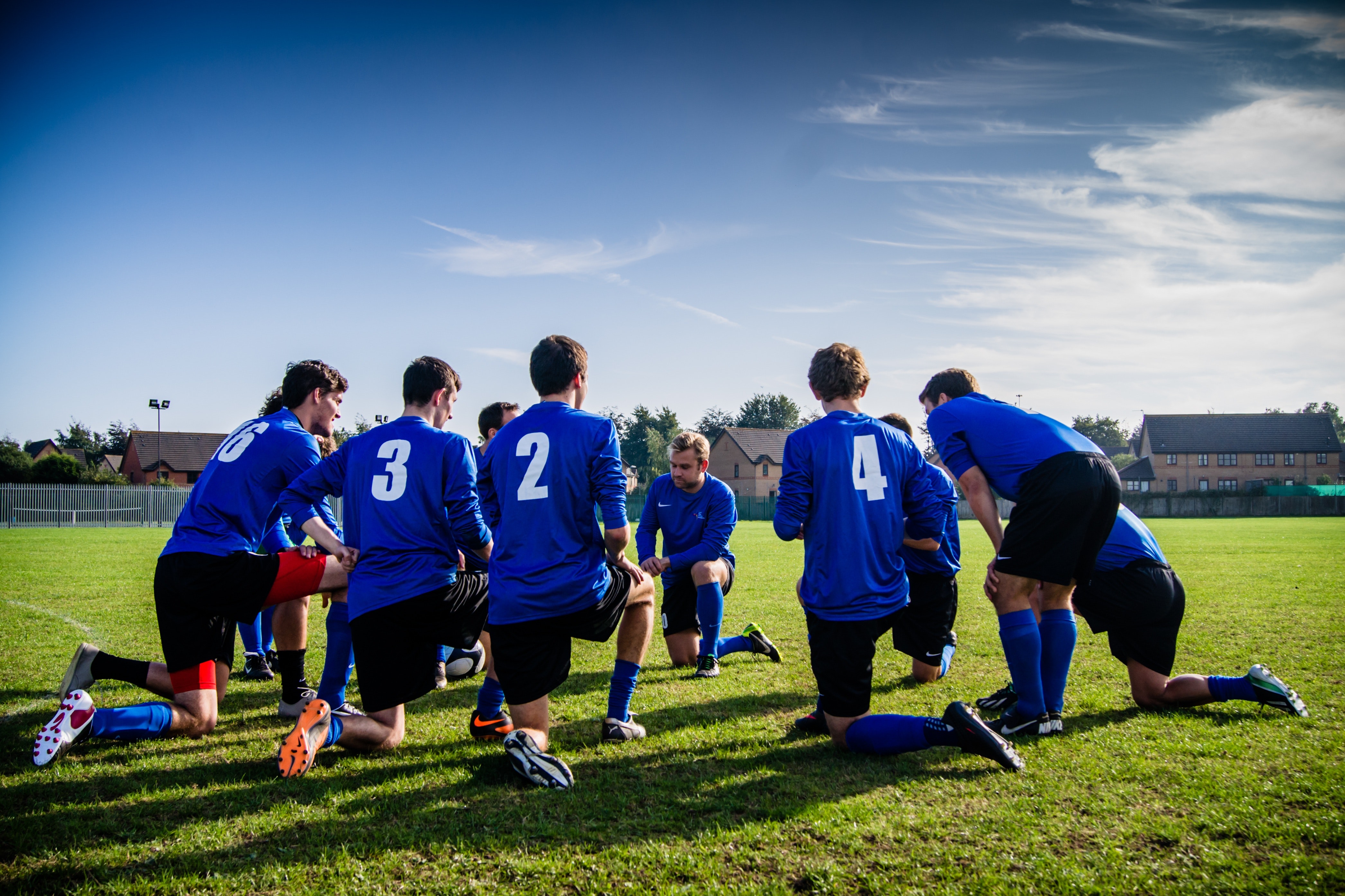 football insurance football club insurance football injury insurance Football team in blue team kit are on their knees talking about football insurance.