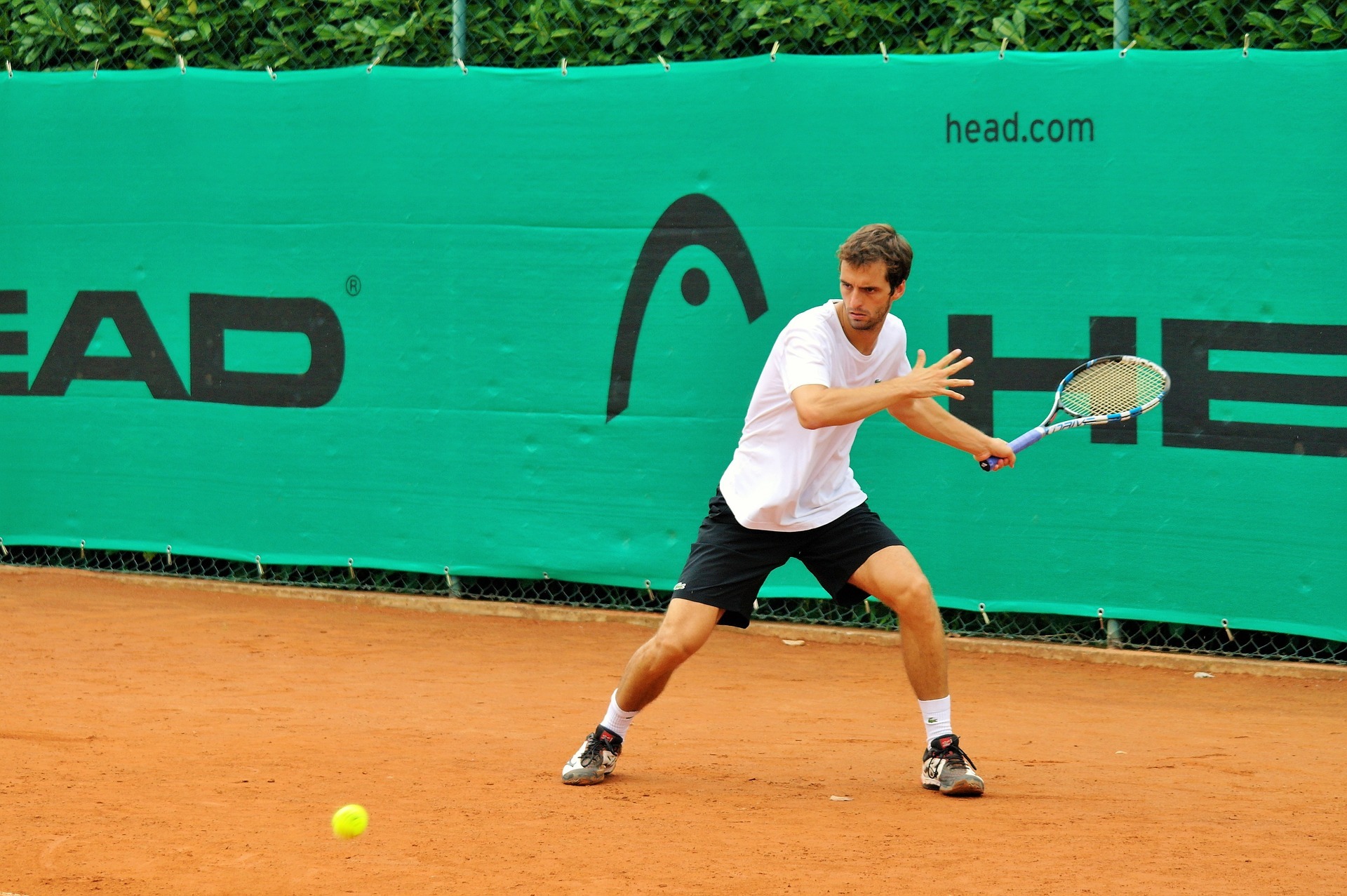 Tennis player in white shirt on clay court with tennis insurance and tennis injury insurance hitting ball The club also has tennis club insurance and is a member of our affiliate sports club insurance scheme.